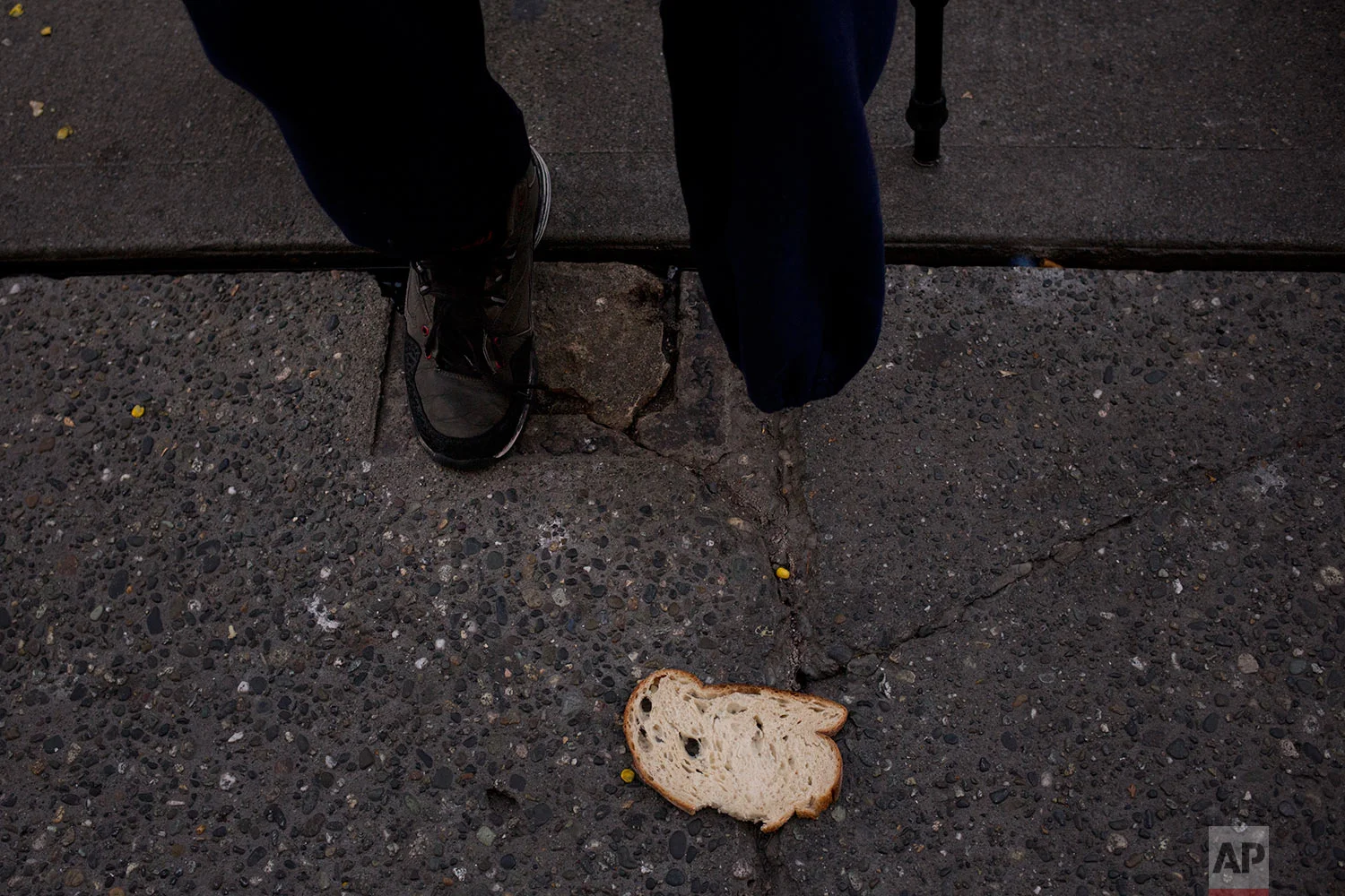 A piece of bread is left on a sidewalk as Korey Epps, a 44-year-old homeless man who had his leg amputated due to an infection while in jail, waits in line to enter Seattle's Union Gospel Mission to spend the night at the shelter Wednesday, Sept. 27, 2017, in Seattle. Serving 14 months in jail, Epps said he lost his job, family and home. "Everyday I feel more more worthless, hopeless. I can't believe this is where my life is," said Epps. "I may as well be on drugs because I lost everything." (AP Photo/Jae C. Hong)