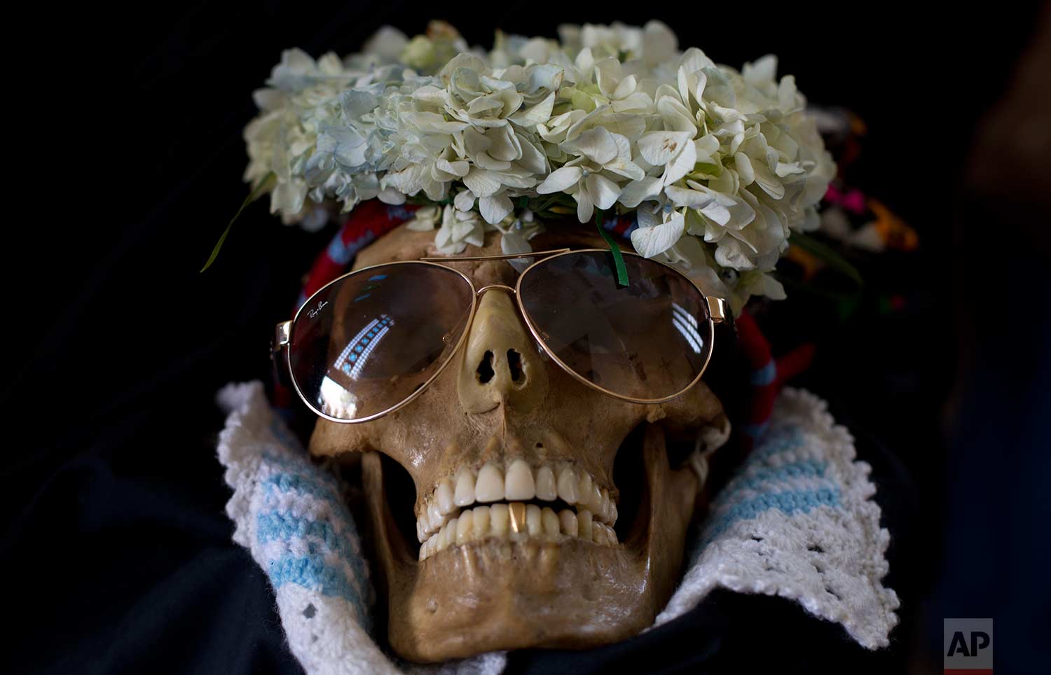 A human skull wearing sun glasses and flowers is displayed outside the General Cemetery chapel during the Natitas Festival in La Paz, Bolivia, Wednesday, Nov. 8, 2017. (AP Photo/Juan Karita)