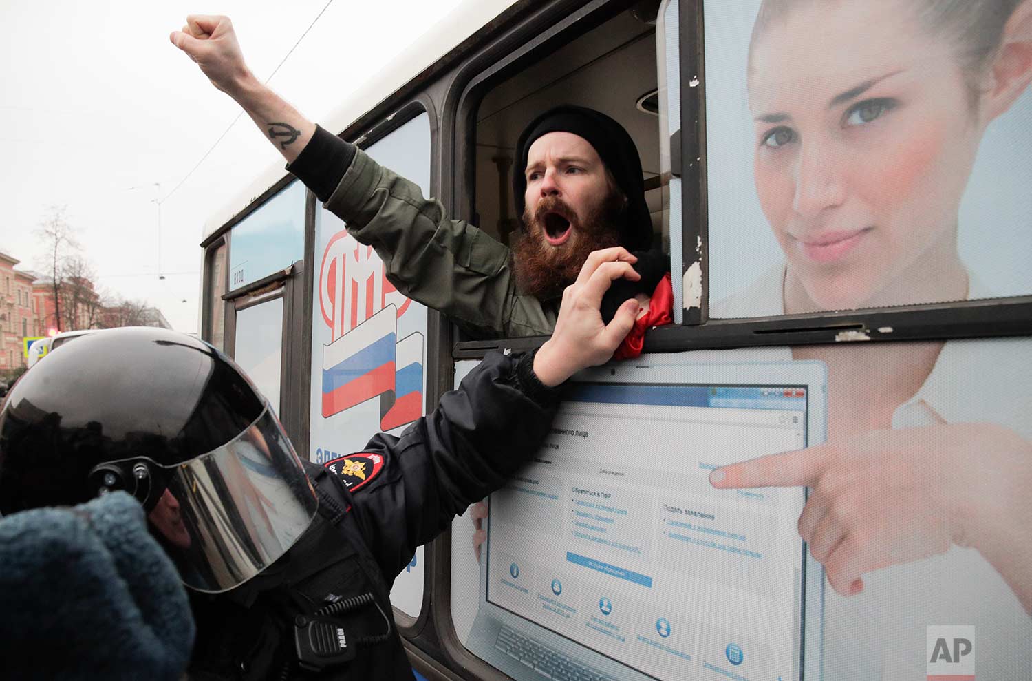 A detained member of the Other Russia movement shouts from a police bus during an unauthorized rally to mark the centenary of the Bolshevik Revolution in St. Petersburg, Russia, on Monday, Nov. 6, 2017. (AP Photo/Dmitri Lovetsky)