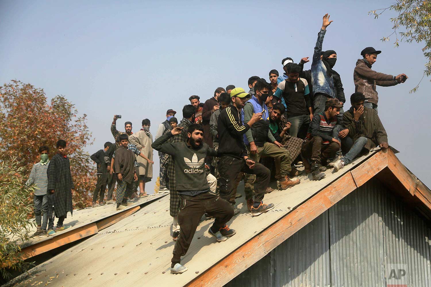 Kashmiri villagers shout pro-freedom slogans from a roof during the funeral procession for killed militant Waseem Ahmad in Drubgam, 48 kilometers (30 miles) south of Srinagar, Indian controlled Kashmir, Tuesday, Nov. 7, 2017. (AP Photo/Mukhtar Khan)