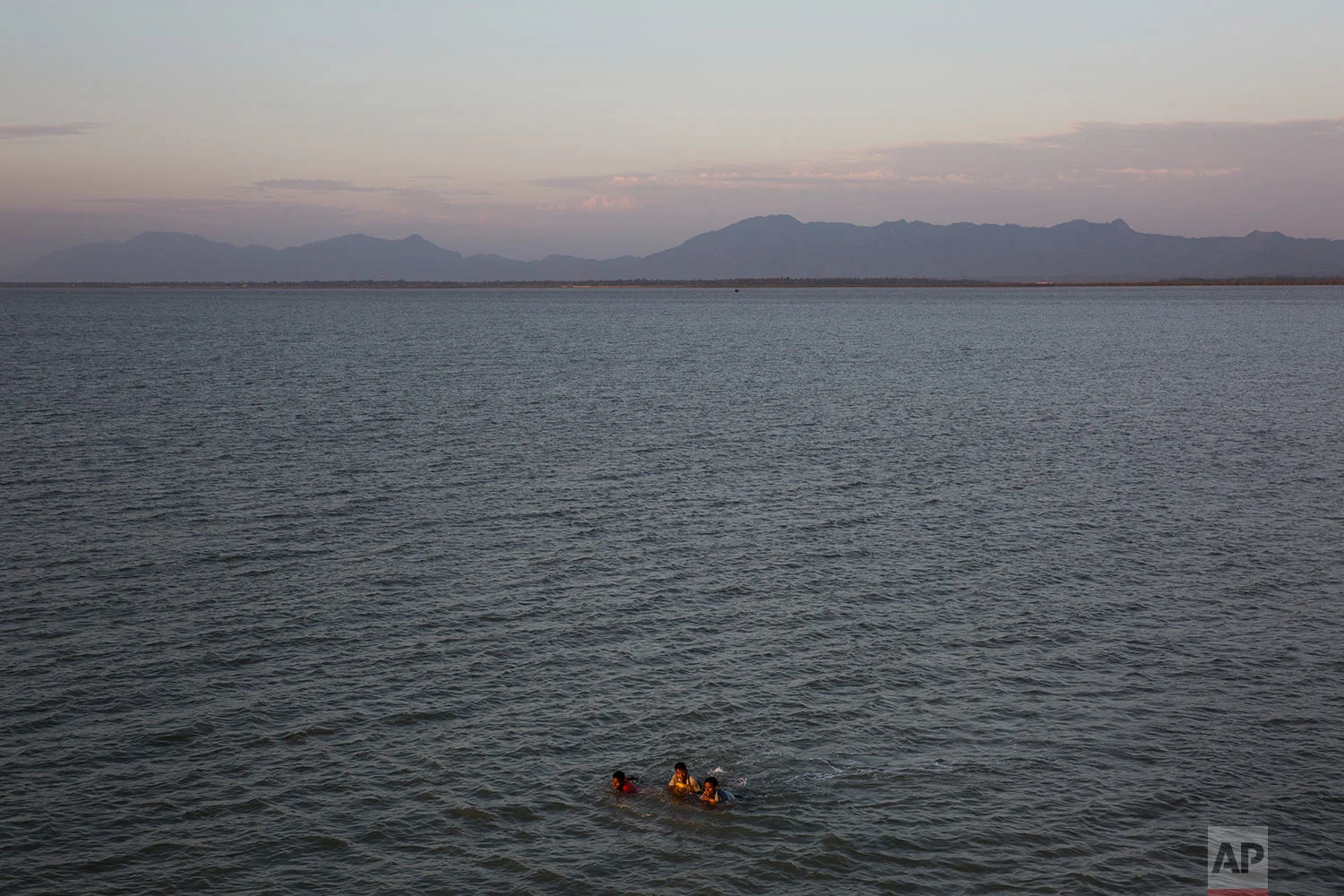 In this Nov. 4, 2017, photo, three Rohingya Muslims swim the Naf river while crossing the Myanmar-Bangladesh border in Shah Porir Dwip, Bangladesh. (AP Photo/Bernat Armangue)