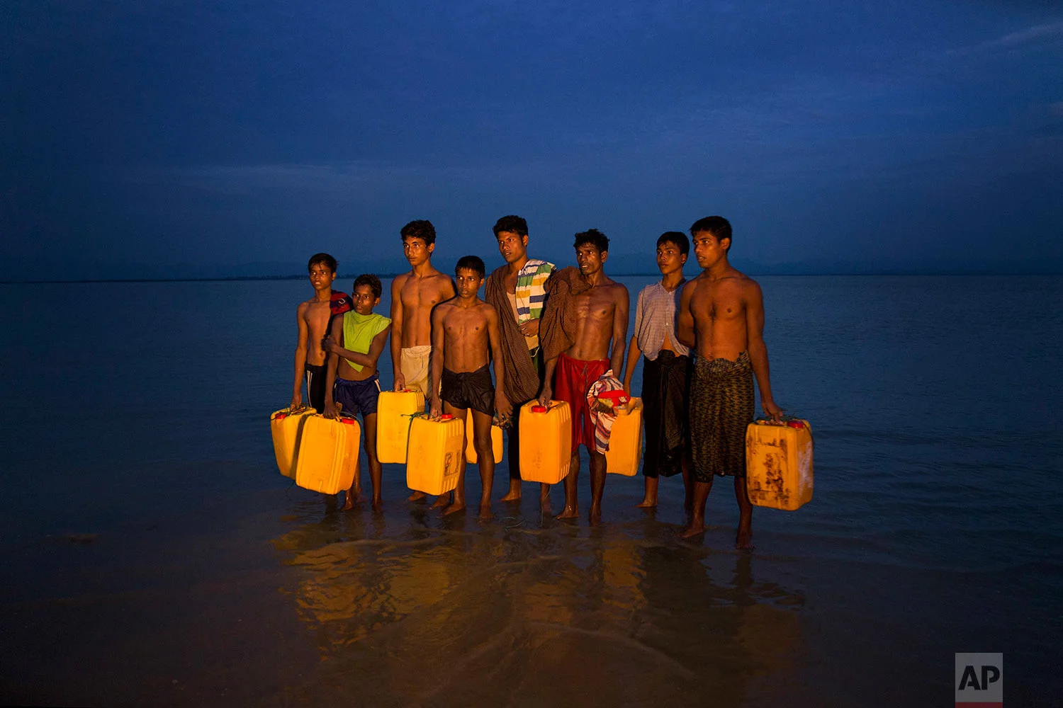 In this Nov. 5, 2017, photo, newly arrived Rohingya Muslims carry yellow plastic drums they used as flotation aids and listen to Bangladeshi authorities, not pictured, after swimming across the Naf river at Shah Porir Dwip, Bangladesh. (AP Photo/Bernat Armangue)