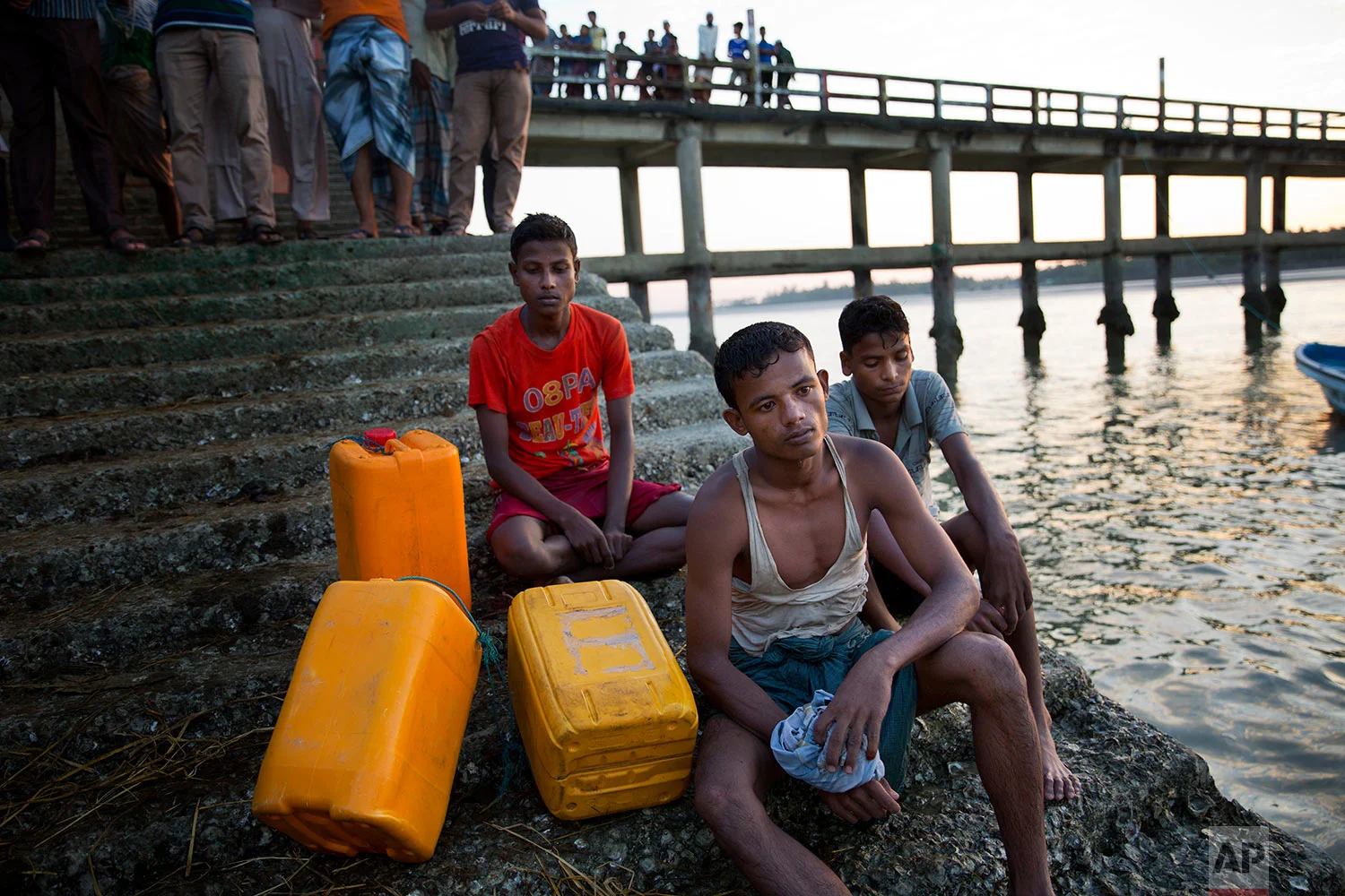 In this Nov. 4, 2017, photo, from left to right: Rohingya Muslims Belal Hussain, 15; Kamal Hussain, 18; and Robiul Hassan, 15; rest after swimming the Naf river in Shah Porir Dwip, Bangladesh. The yellow plastic drums in picture were used as a flotation aid. (AP Photo/Bernat Armangue)