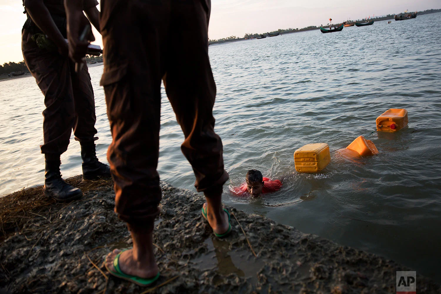 In this Nov. 4, 2017, photo, Rohingya Muslim Belal Hussain, 15, center, arrives at Shah Porir Dwip, Bangladesh, after swimming Naf river. The Naf river is a natural border between Myanmar and Bangladesh. (AP Photo/Bernat Armangue)