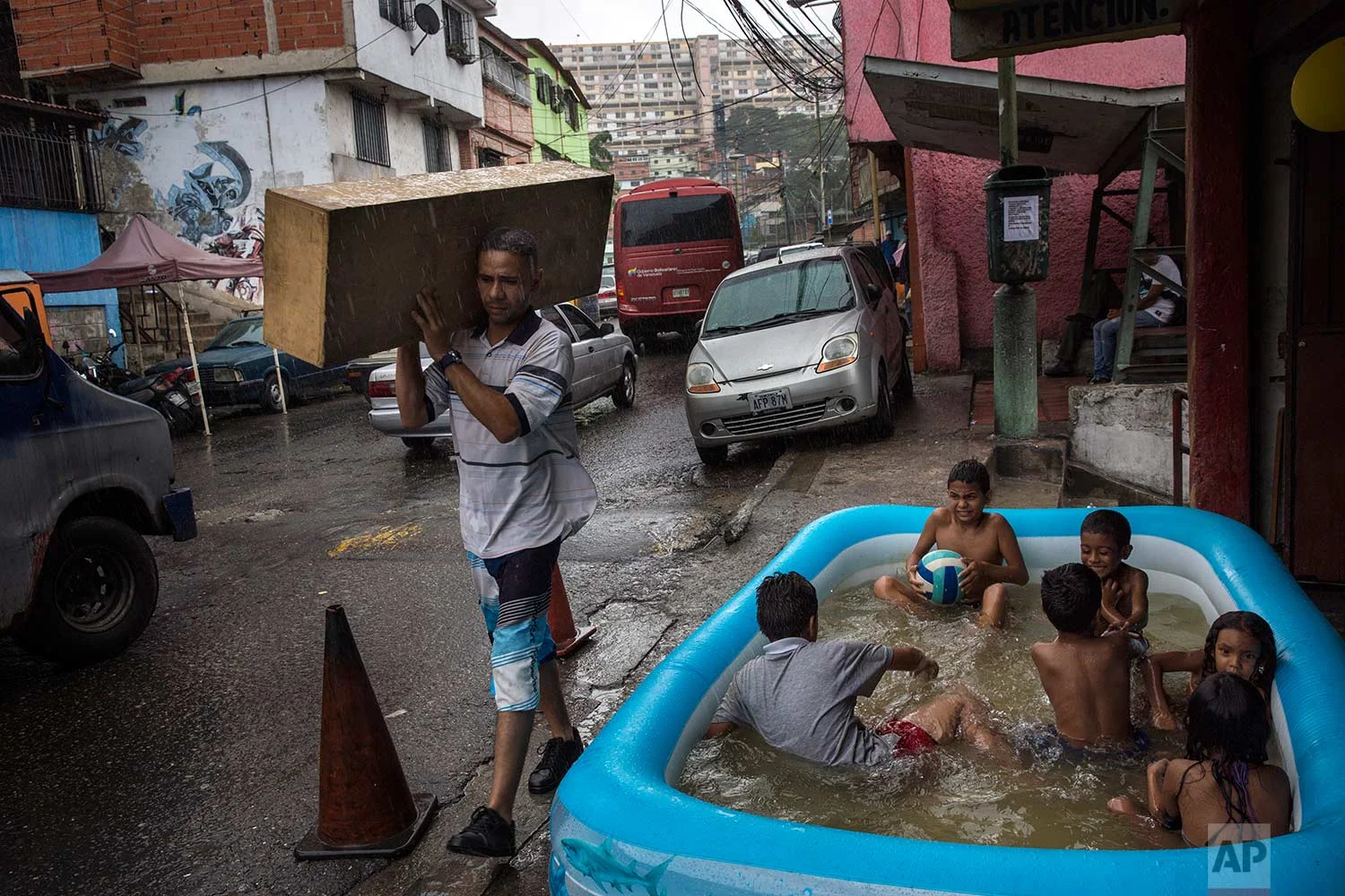 Children play in an inflatable swimming pool in the working class 23 de Enero neighborhood as it rains lightly in Caracas, Venezuela, Saturday, Oct. 21, 2017. (AP Photo/Rodrigo Abd)