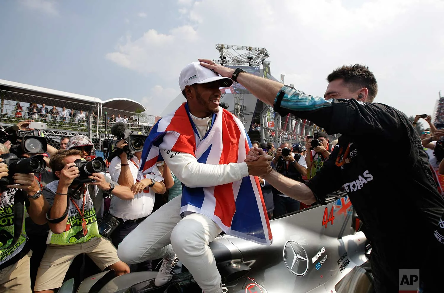British driver Lewis Hamilton celebrates wining his fourth Formula One championship with a member of his team after the Mexican Formula One Grand Prix auto race at the Hermanos Rodriguez racetrack in Mexico City, Sunday, Oct. 29, 2017. (AP Photo/Moises Castillo)