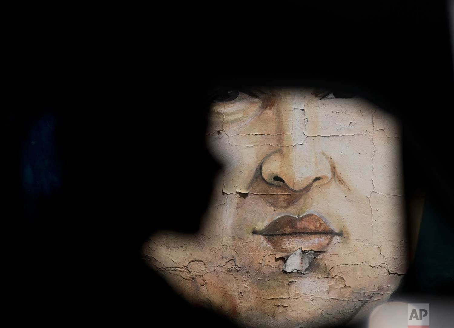 A mural of late President Hugo Chavez is seen as a man drives a car in Caracas, Venezuela, Saturday, Oct 14, 2017. (AP Photo/Ariana Cubillos)