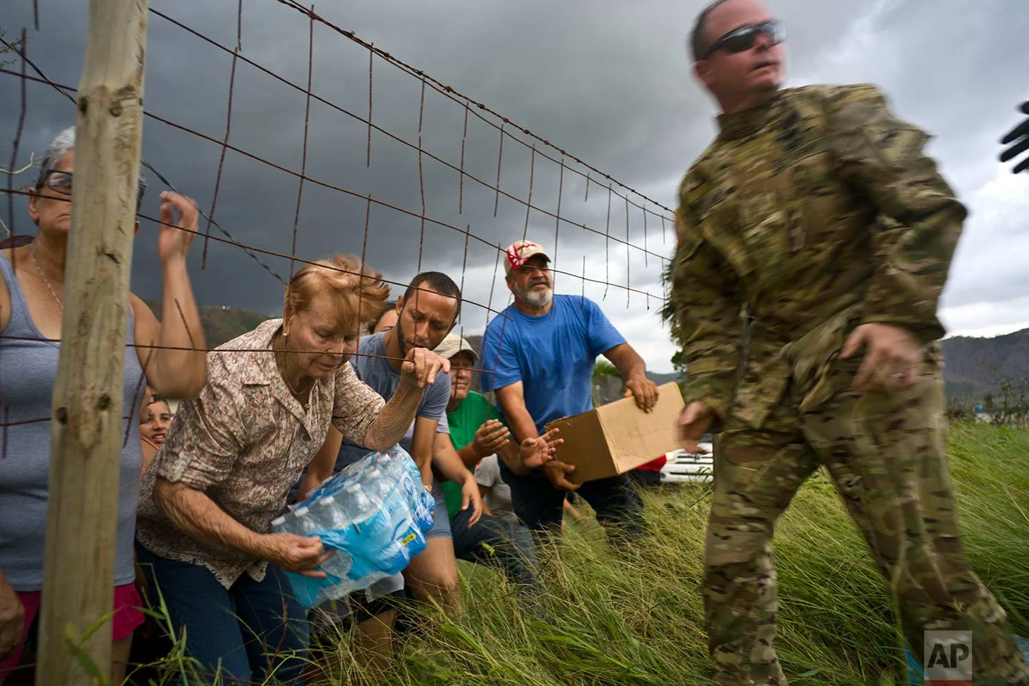 A member of the Puerto Rican National Guard delivers food and water brought via helicopter to victims of Hurricane Maria, to the San Lorenzo neighborhood of Morovis, Puerto Rico, Saturday, Oct. 7, 2017. (AP Photo/Ramon Espinosa)