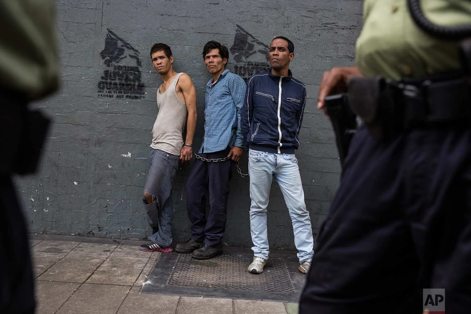 Suspected thieves chained together look at police after they were detained in downtown in Caracas, Venezuela, Wednesday, Oct. 25, 2017. (AP Photo/Rodrigo Abd)