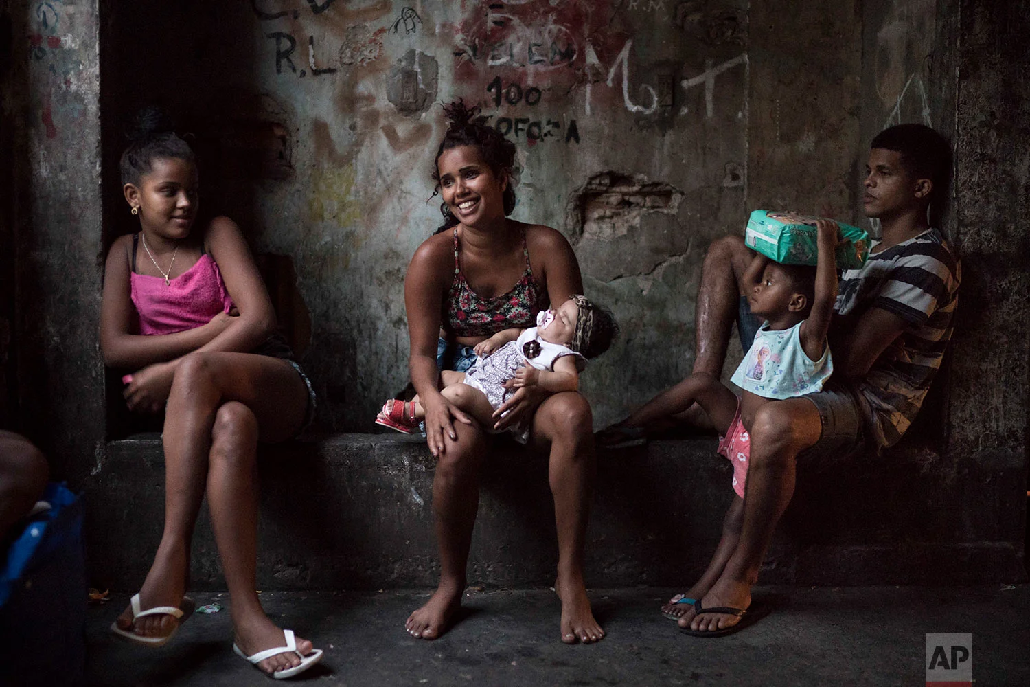 In this Sept. 9, 2017 photo, residents sit in a corridor inside a squatter building that used to house the Brazilian Institute of Geography and Statistics (IBGE) in the Mangueira slum of Rio de Janeiro, Brazil. Despite the hardscrabble existence, there is a strong sense of community among the hundreds of people occupying the building. (AP Photo/Felipe Dana)