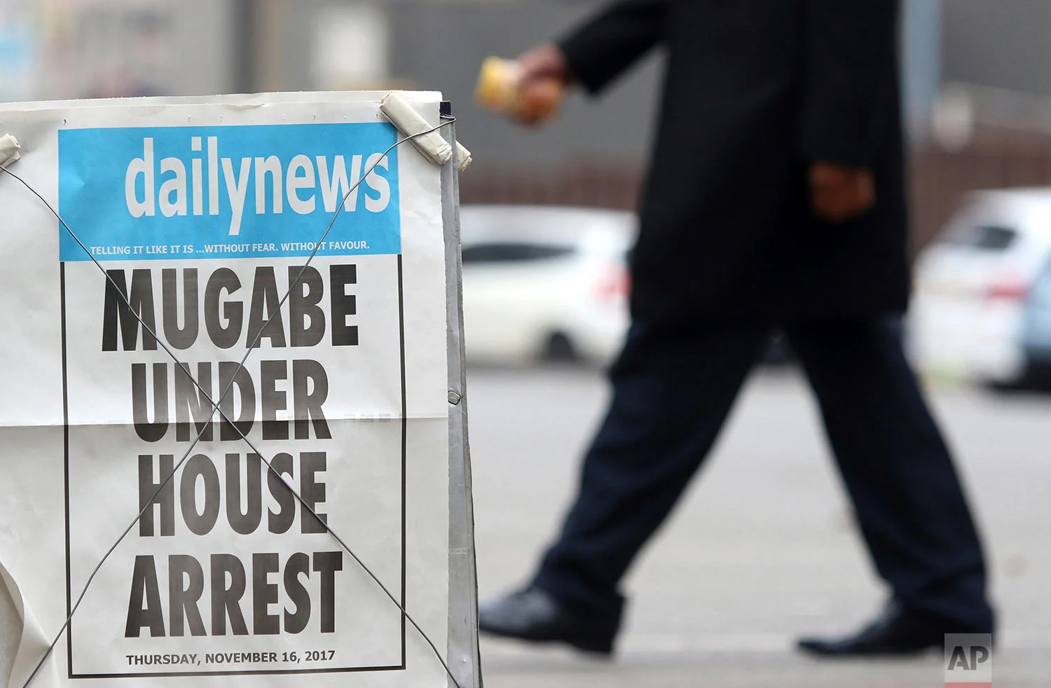 A person passes a newspaper headline in Harare, Zimbabwe, Thursday, Nov. 16, 2017. People across the country are starting another day of uncertainty amid quiet talks to resolve the country's political turmoil and the likely end of President Robert Mugabe's decades-long rule. Mugabe has been in military custody and there is no sign of the recently fired deputy Emmerson Mnangagwa, who fled the country last week. (AP Photo)