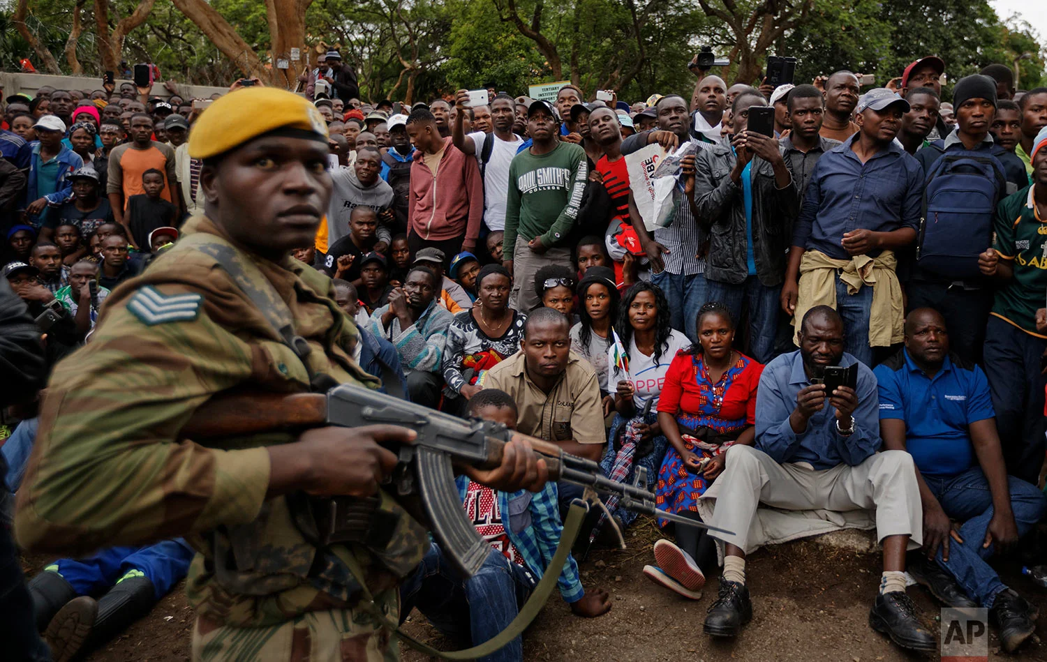 An army soldier stands guard as protesters demanding President Robert Mugabe stands down gather on the road leading to State House in Harare, Zimbabwe Saturday, Nov. 18, 2017. In a euphoric gathering that just days ago would have drawn a police crackdown, crowds marched through Zimbabwe's capital on Saturday to demand the departure of President Robert Mugabe, one of Africa's last remaining liberation leaders, after nearly four decades in power. (AP Photo/Ben Curtis)