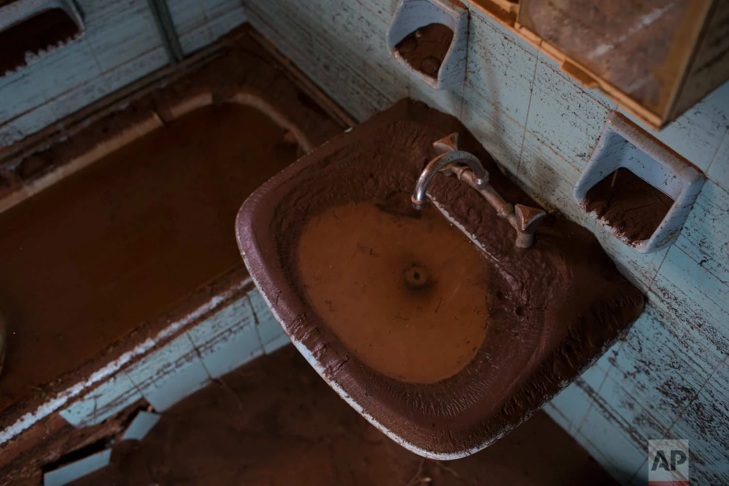 In this Tuesday , Nov. 21, 2017 photo a sink and a bathtub is covered with mud into a flood-damaged home in the town of Mandra , west of Athens. (AP Photo/Petros Giannakouris)