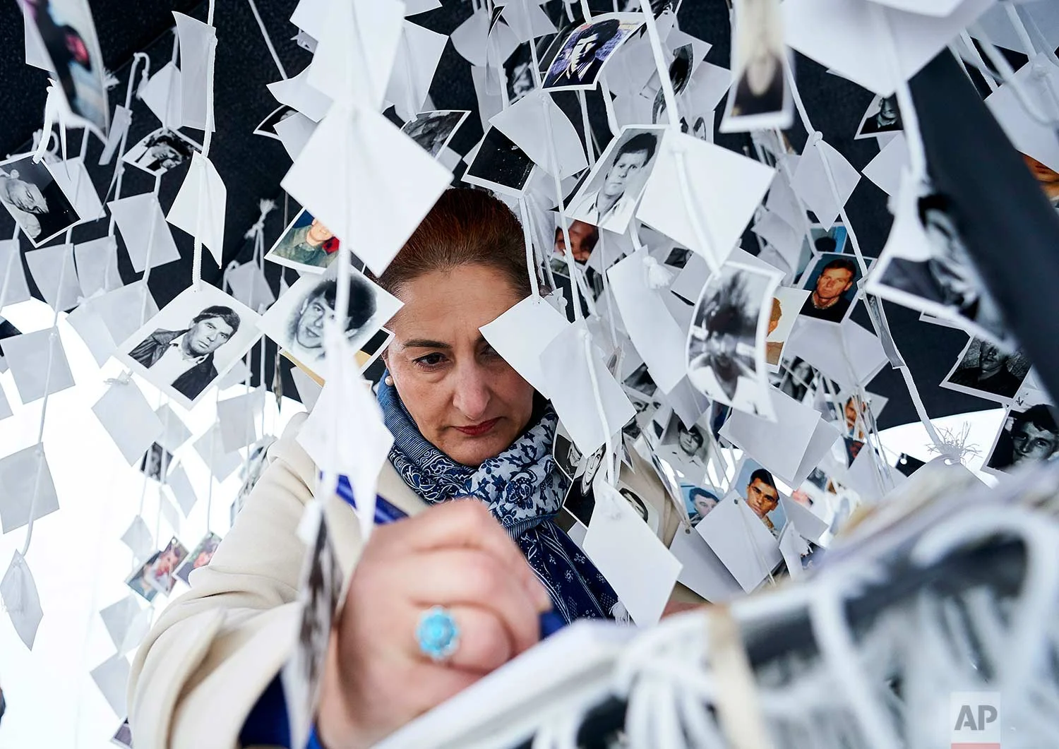 A woman writes in a book inside a traveling monument called 'Prijedor 92' outside the Yugoslav War Crimes Tribunal, ICTY, as she waits for the verdict to be handed down in the genocide trial against former Bosnian Serb military chief Ratko Mladic, in The Hague, Netherlands, Wednesday Nov. 22, 2017. (AP Photo/Phil Nijhuis)