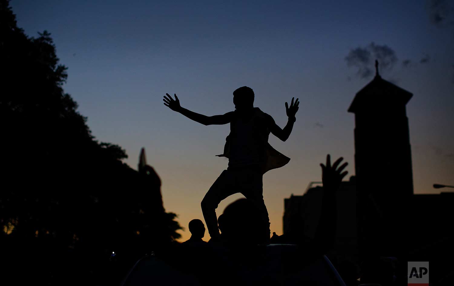  A Zimbabwean dances on the roof of a vehicle as he and others celebrate outside the parliament building immediately after hearing the news that President Robert Mugabe had resigned, in downtown Harare, Zimbabwe Tuesday, Nov. 21, 2017. (AP Photo/Ben 
