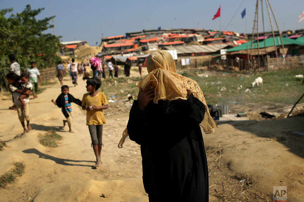  A Rohingya Muslim woman covers her face from the afternoon dust and heat as she walks through Jamtoli refugee camp on Monday, Nov. 27, 2017, in Bangladesh. Since late August, more than 620,000 Rohingya have fled Myanmar's Rakhine state into neighbor