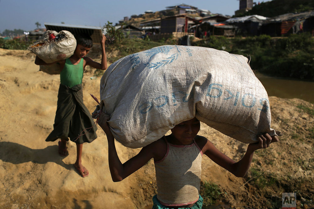  Rohingya Muslim children carry rice and a solar panel which they collected from an aid distribution center on Tuesday, Nov. 21, 2017, in Kutupalong refugee camp in Bangladesh. Since late August, more than 620,000 Rohingya have fled Myanmar's Rakhine