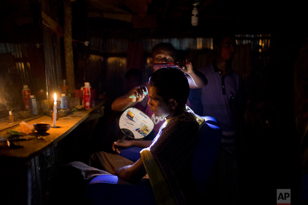  A Rohingya Muslim gets his hair cut in a makeshift barber shop that is lit with a candle and a torch light at Jamtoli refugee camp, Friday, Nov. 24, 2017, in Bangladesh. Since late August, more than 620,000 Rohingya have fled Myanmar's Rakhine state
