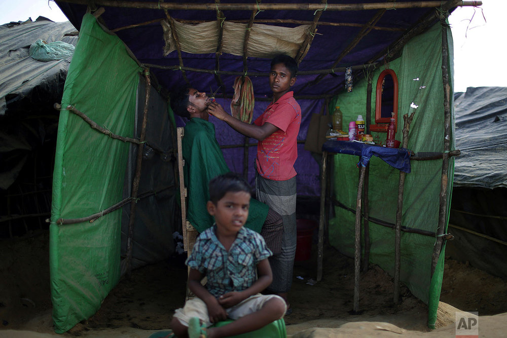  In this Sunday, Nov. 19, 2017, photo, a Rohingya Muslim child sits in front of a barber's tent in Kutupalong refugee camp in Bangladesh.  More than 620,000 Rohingya have fled Rakhine for neighbouring Bangladesh since late August 2017, when the milit