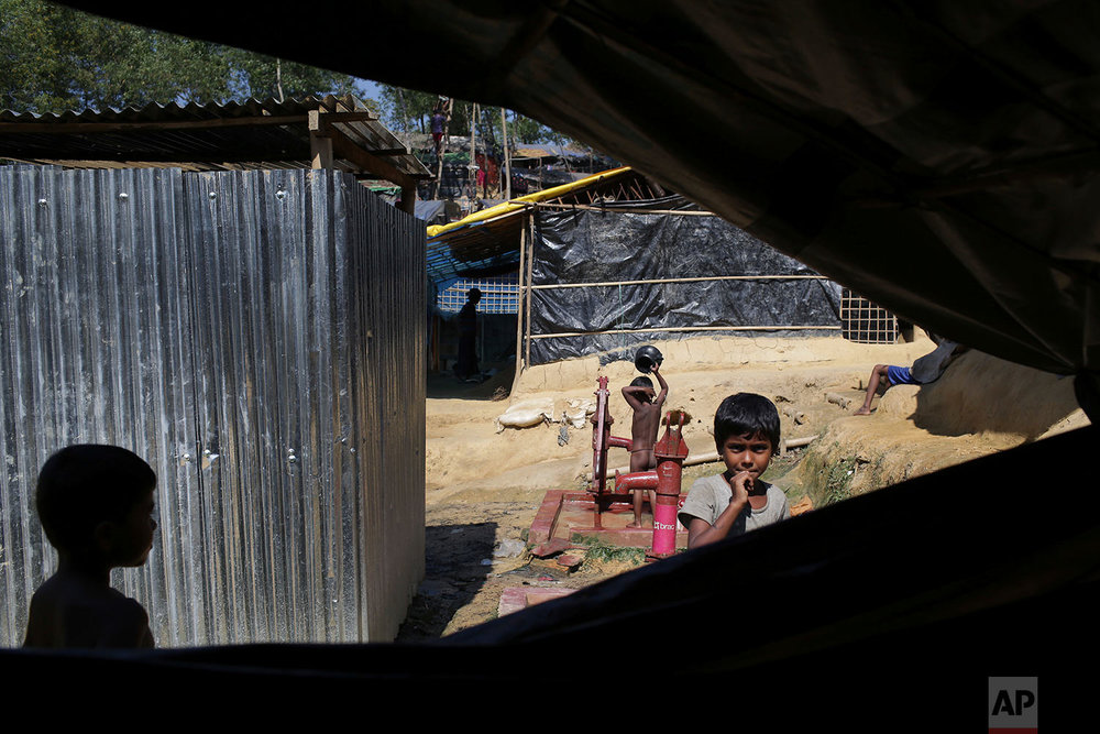  Rohingya Muslim children walk around their tents while one child bathes in Kutupalong Refugee camp on Monday, Nov. 20, 2017, in Bangladesh. More than 620,000 Rohingya have fled Rakhine for neighboring Bangladesh since late August, when the military 