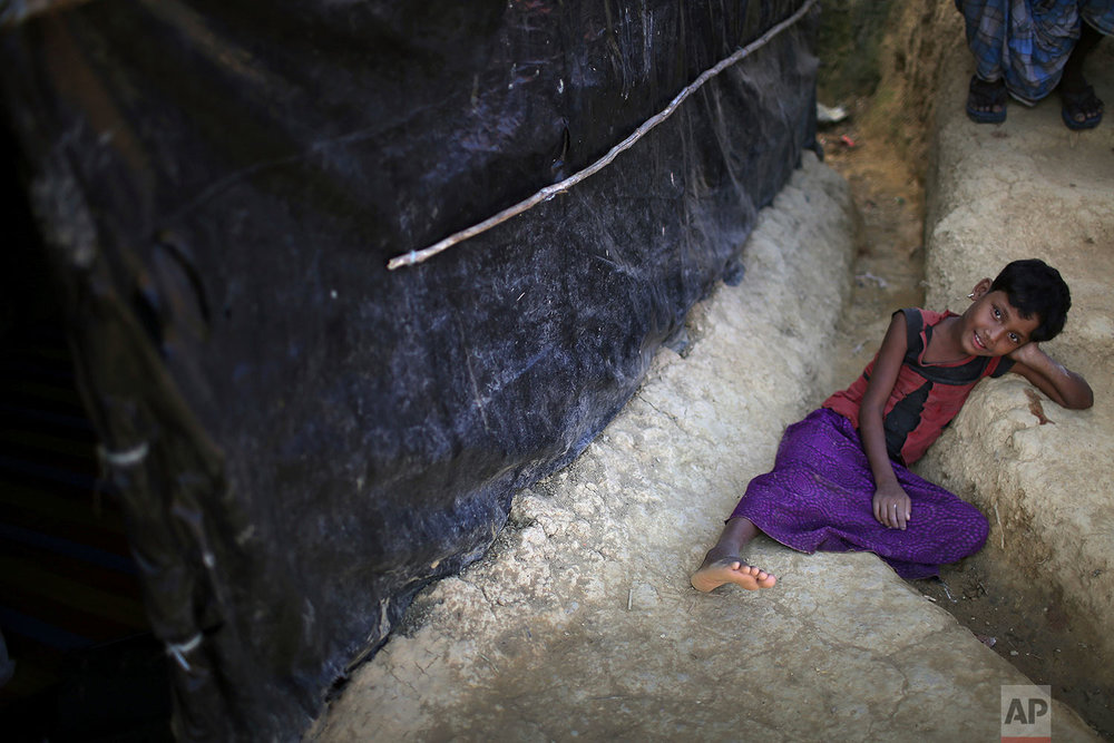  In this Sunday, Nov. 19, 2017, photo, a Rohingya Muslim girl rests in the drain of a mud track in Kutupalong refugee camp in Bangladesh.  More than 620,000 Rohingya have fled Rakhine for neighbouring Bangladesh since late August 2017, when the milit