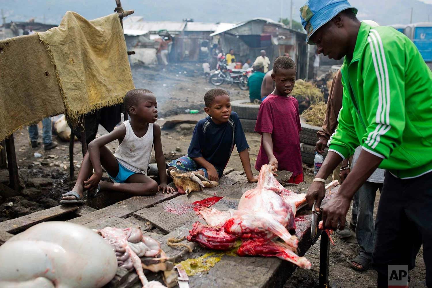 In this Nov. 10, 2017 photo, children watch a butcher portion a goat carcass at the La Saline slaughterhouse, in Port-au-Prince, Haiti. (AP Photo/Dieu Nalio Chery)