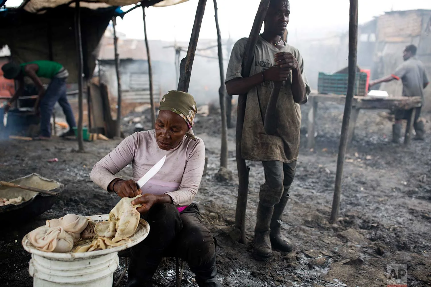 In this Nov. 10, 2017 photo, Lisianne Chalemagne, 65, removes waste from goat intestines, at the La Saline slaughterhouse in Port-au-Prince, Haiti. Chalemagne has worked at the open-air market for 32 years. She hopes the La Saline will one day be transformed into a modern, safe market. (AP Photo/Dieu Nalio Chery)