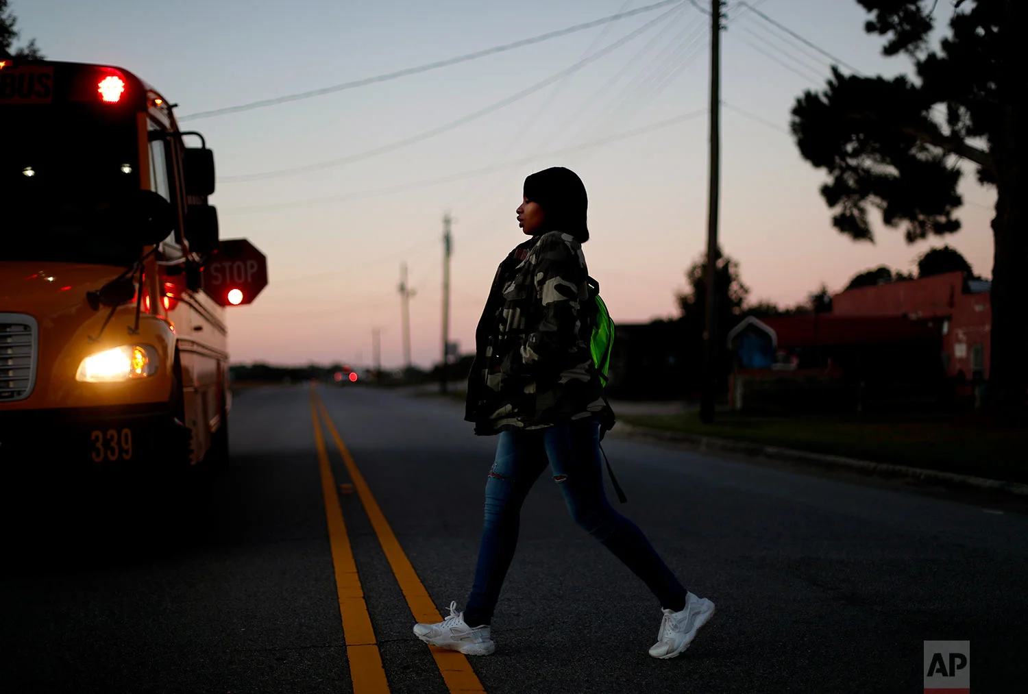 South Robeson High School student and cheerleader Aajah Washington crosses the street to catch the school bus outside her home in Rowland, N.C. (AP Photo/David Goldman)