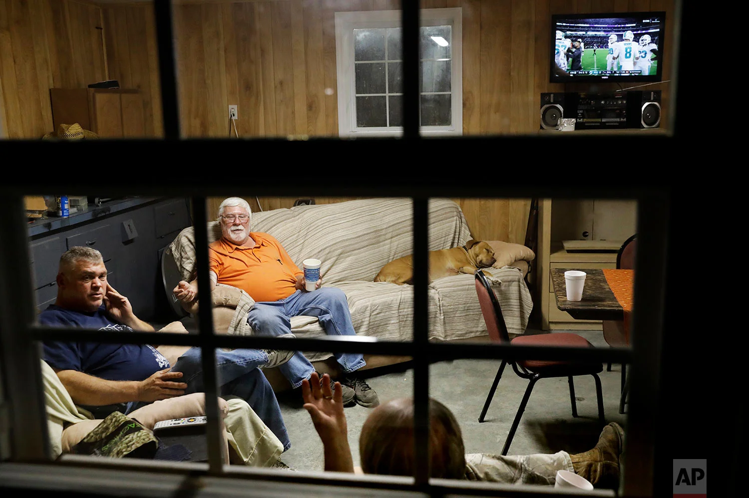 Cary Lewis, bottom right, and Ricky Phillips, left, watch an NFL football game at the home of Buddy Jones, during their weekly dinner gathering in Lumberton, N.C. (AP Photo/David Goldman)