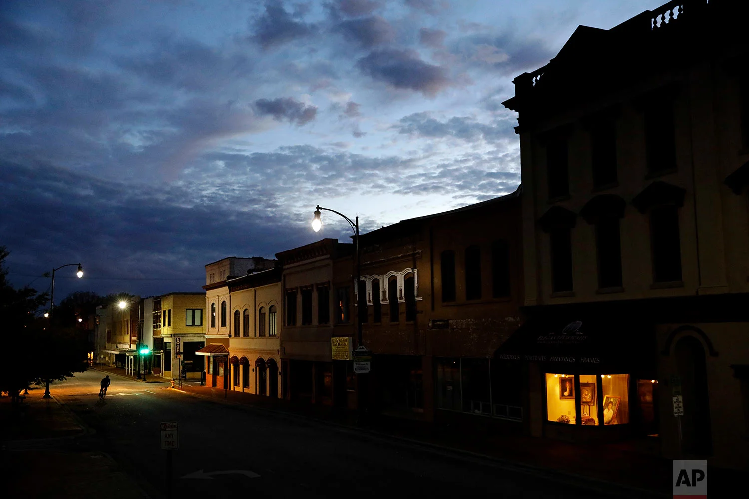 The storefront window of a portrait studio is lit up along a downtown street at dusk in Lumberton, N.C., Saturday, Oct. 28, 2017. (AP Photo/David Goldman)