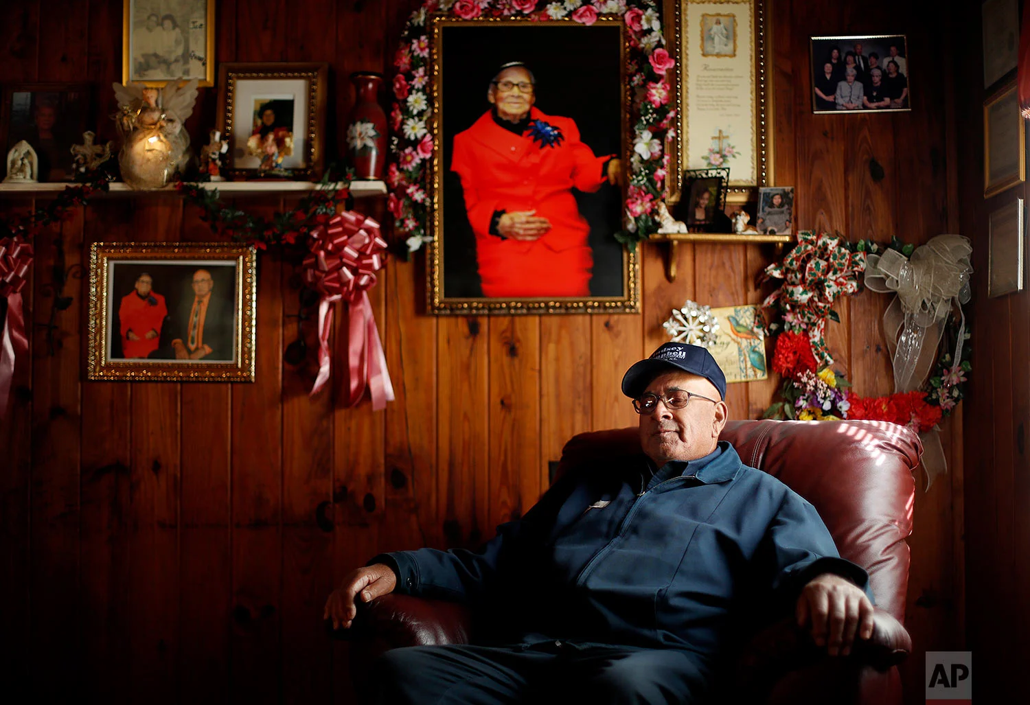Horace Locklear sits for a portrait under a picture of his late wife Quessie, who passed last year after 53 years of marriage, in Fairmont, N.C., Monday, Oct. 30, 2017. Locklear, a member of the Lumbee Native American tribe, says that when he was young and growing up in Robeson County he remembers having to get his food from a back window because he and his family couldn't dine in many restaurants. "I just couldn't really understand why people couldn't get along. You know, mix and mingle." But he says it's gotten better over the years and he has friends of many races. While he voted for President Obama, he voted for President Trump because he thinks he can bring jobs to the region – and also, based on his reading of the Bible, because he doesn't think a woman should be president. (AP Photo/David Goldman)