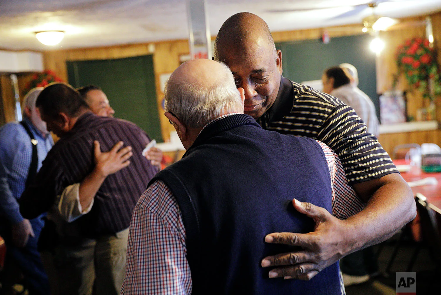 Walker Davis, right, embraces Bobby Martin at a prayer breakfast at a diner in Lumberton, N.C., Saturday, Oct. 28, 2017. "We love this isolation because we're comfortable but the lord didn't send Jesus to make us comfortable. Jesus came to change our mindsets," said Davis speaking before the weekly meeting made up of whites, blacks and Native Americans. "It's a unified body here but we're all from different walks of life and different ministries. This is why I love it here. This is truly a house united, not a house divided." (AP Photo/David Goldman)
