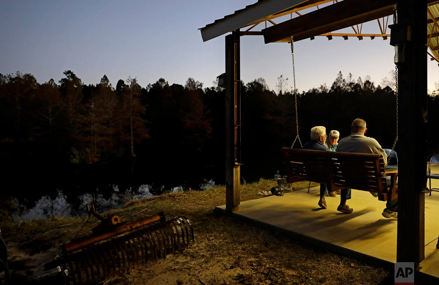 Elton Connor, rear, joins Bruce Kinlaw and Ricky Phillips on the patio before dinner is ready at their weekly gathering at a home in Lumberton, N.C., Thursday, Oct. 26, 2017. Sometimes, the men watch Fox News and talk politics. These days, they turn on football and bemoan the national anthem protests that, to them, represent an unraveling of American values of tradition, patriotism and honor. (AP Photo/David Goldman)