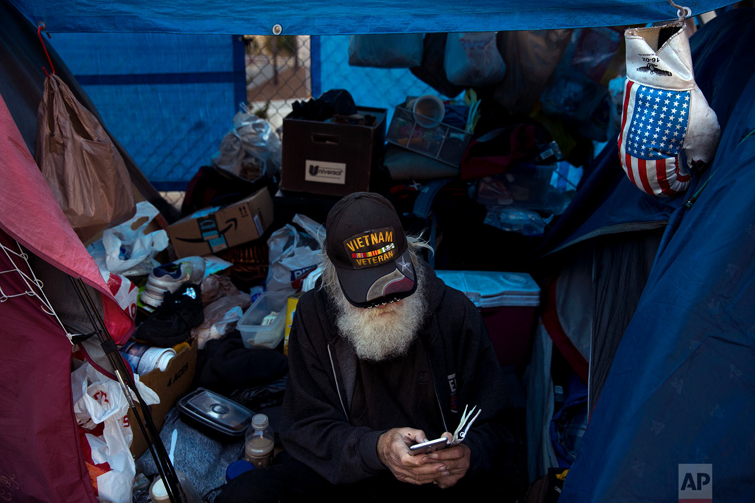  Theodore Neubauer, a 78-year-old Vietnam War veteran, who is homeless, looks at his smartphone while passing time in his tent Friday, Dec. 1, 2017, in Los Angeles. "Well, there's a million-dollar view," said Neubauer on what it's like to be homeless
