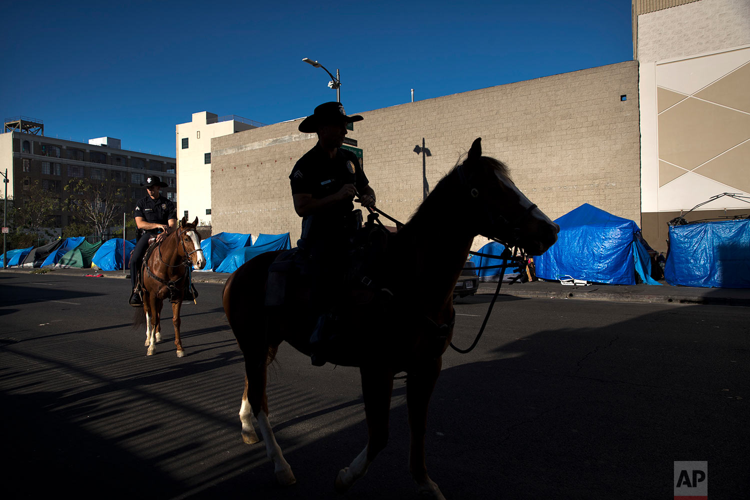  Tents belonging to homeless people are covered with tarps as Los Angeles police officers on horses patrol in the Skid Row area of downtown Los Angeles Friday, Dec. 1, 2017. A homeless crisis of unprecedented proportions is rocking the West Coast, an