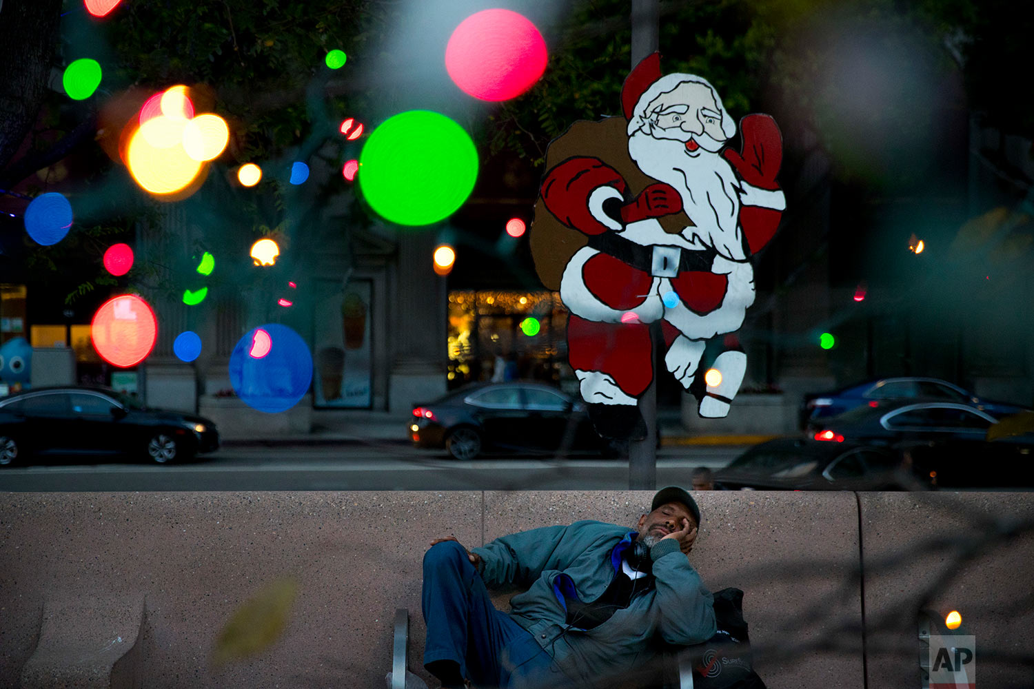  Homeless man Alonzo Harrison, 47, takes a nap on a bench at Pershing Square decorated with Christmas lights in the background on Monday, Dec. 4, 2017, in Los Angeles. A homeless crisis of unprecedented proportions is rocking the West Coast, and its 