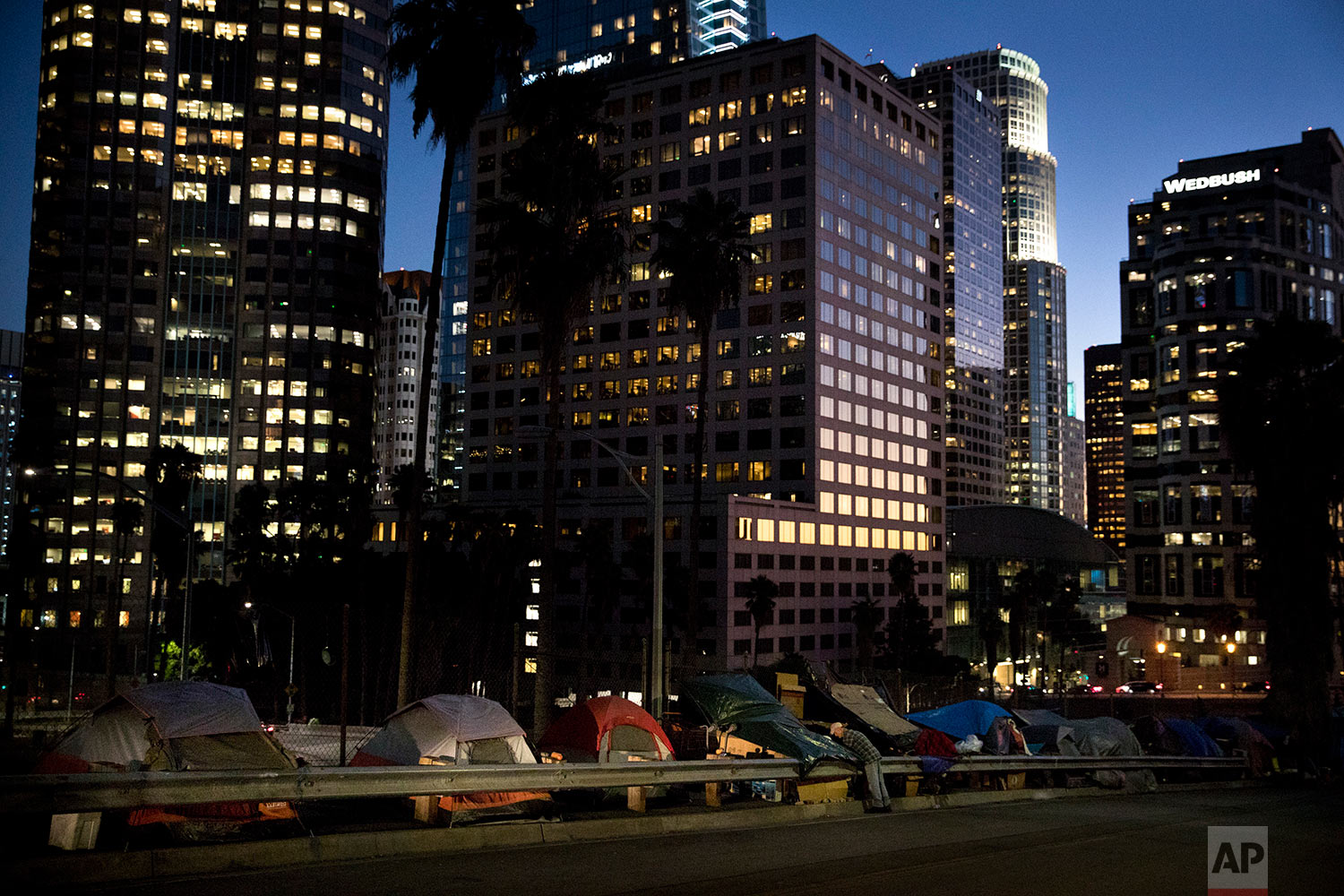  Homeless tents are dwarfed by skyscrapers as 63-year-old Vincent, who only gave his first name, sorts his belongings Friday, Dec. 1, 2017, in Los Angeles. Vincent said he thought he was bulletproof and never had to worry about getting a job as a you