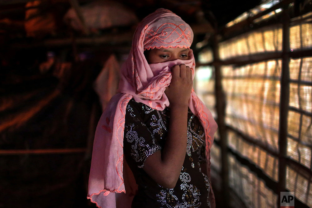  In this Sunday, Nov. 19, 2017, photo, R, 13, covers her face with her headscarf while being photographed in her tent in Kutupalong refugee camp in Bangladesh. (AP Photo/Wong Maye-E) 