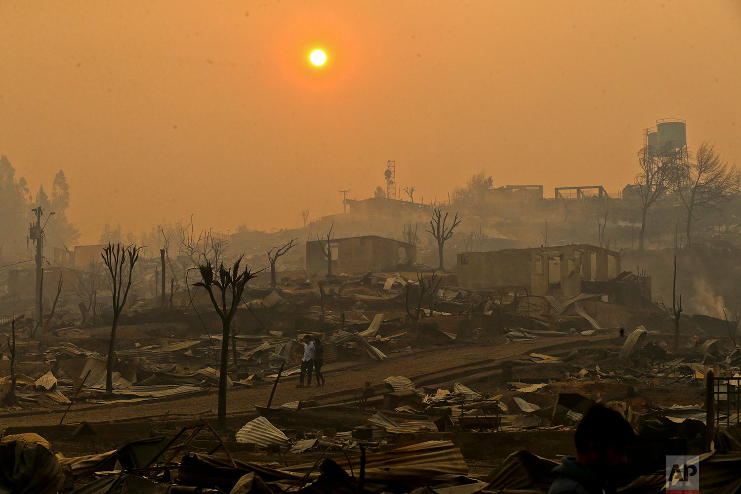 A couple walks through a neighborhood destroyed by wildfires in Chile's Santa Olga community, Thursday, Jan. 26, 2017. The town was consumed by the country's worst wildfires, engulfing the post office, a kindergarten and hundreds of homes. (AP Photo/Esteban Felix)