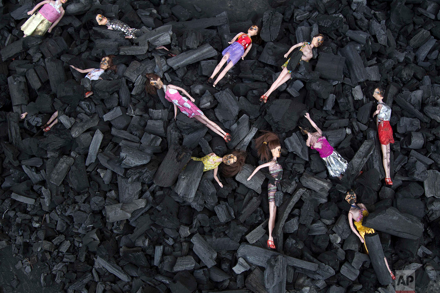 Charred-stained dolls placed on a bed of charcoal are part of artists’ installation placed at the front gate of presidential house in remembrance of the victims of a fire at a girls' home in Guatemala City, Thursday, March 9, 2017. About 700 children lived in the Virgen de la Asunción Safe Home with a maximum capacity for 500. Some dormitories housed more than twice the number of children authorized for the space. (AP Photo/Luis Soto)