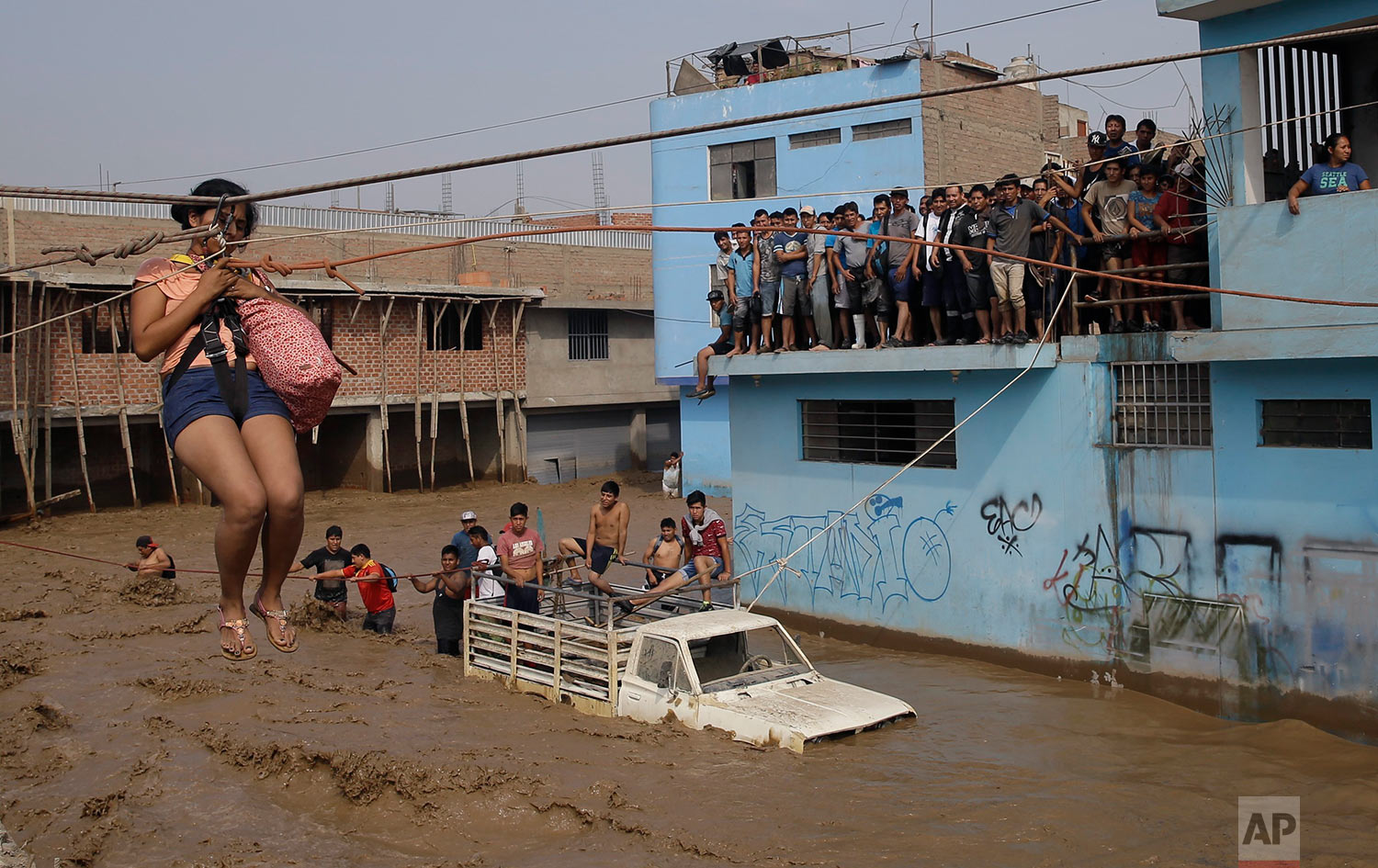 A woman is pulled to safety in a zipline harness in Lima, Peru, Friday, March 17, 2017. Intense rains and mudslides over three days wrought havoc around the Andean nation and caught residents in Lima, a desert city of 10 million where it almost never rains, by surprise. (AP Photo/Martin Mejia)