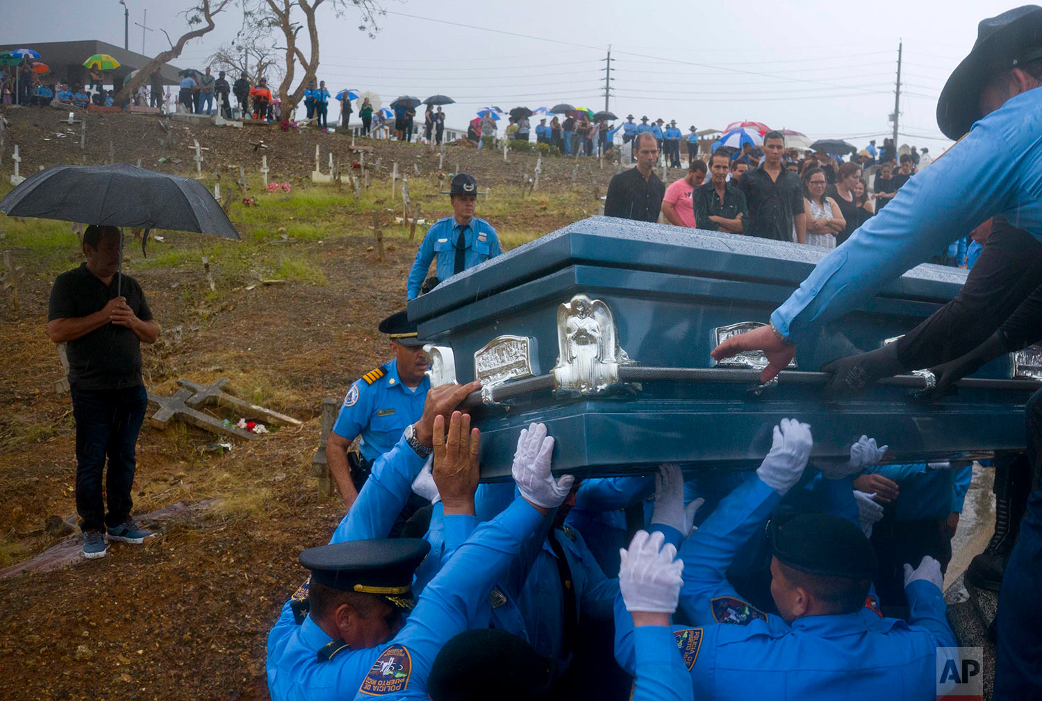 Police lift the coffin of fellow officer Luis Angel Gonzalez Lorenzo, who was killed while trying to cross a river in his car during the passage of Hurricane Maria, as they bury him in Aguada, Puerto Rico, Friday, Sept. 29, 2017. The Category 4 storm destroyed tens of thousands of homes and killed at least 55 people across the U.S. territory. (AP Photo/Ramon Espinosa)