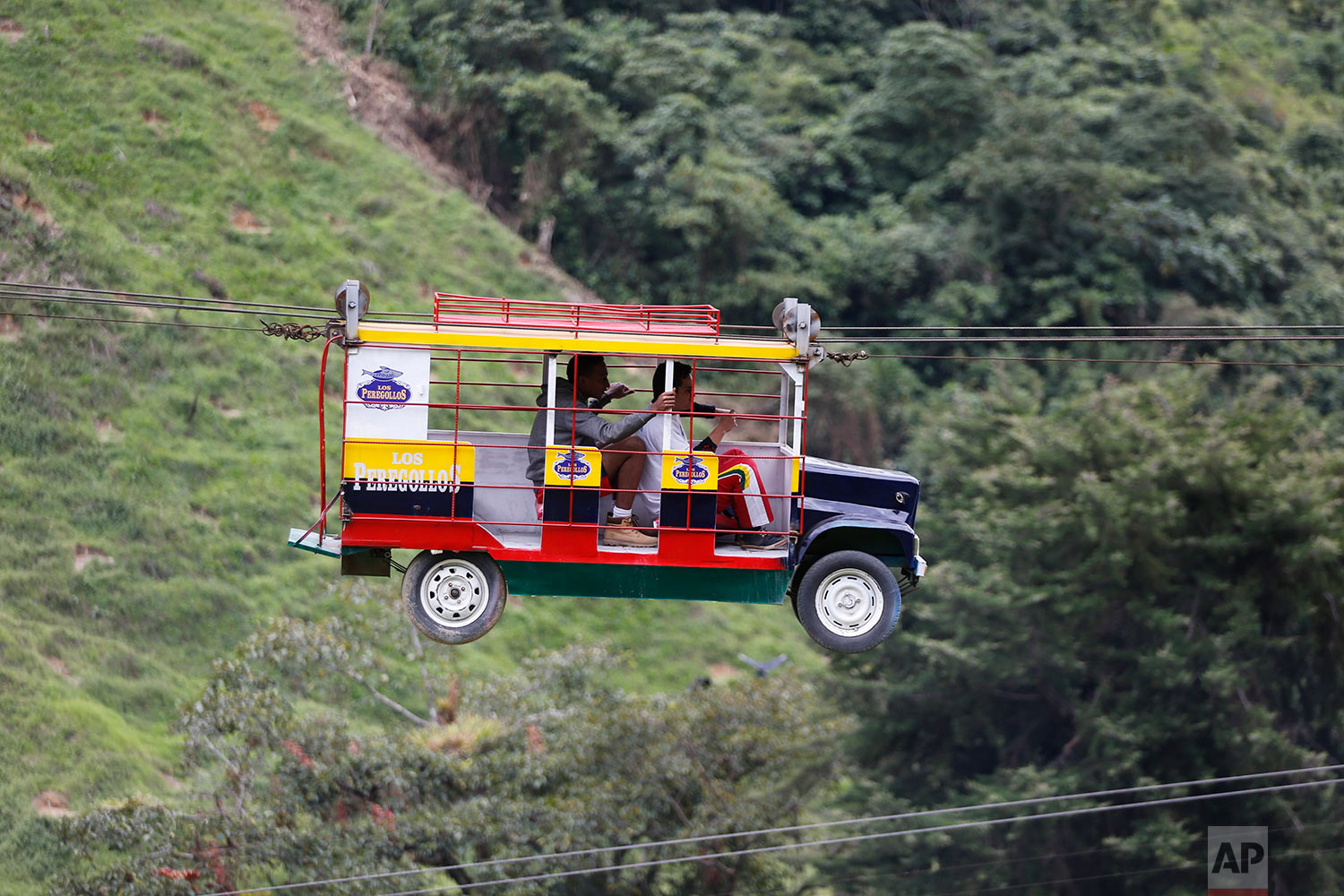 Tourists ride a cable car in the form a of a Chiva, a bus used to serve rural routes, in Pitalito, Colombia, Tuesday, April 5, 2017. The ride called "La Chiva Voladora" costs about $0.70 and you zip along about 800 meters from one side of a hill to another. (AP Photo/Fernando Vergara)