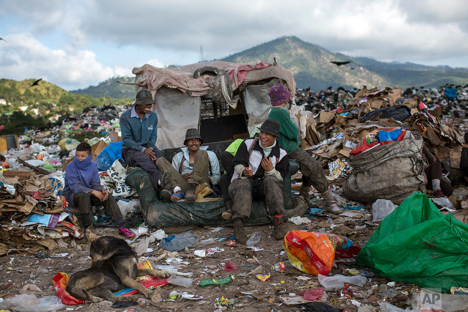 Men and boys joke around as they take a break from collecting plastic and cardboard to resell, at "El Crematorio" or The Crematory, the biggest dump on the outskirts of Tegucigalpa, Honduras, Friday, Nov. 24, 2017. (AP Photo/Rodrigo Abd)