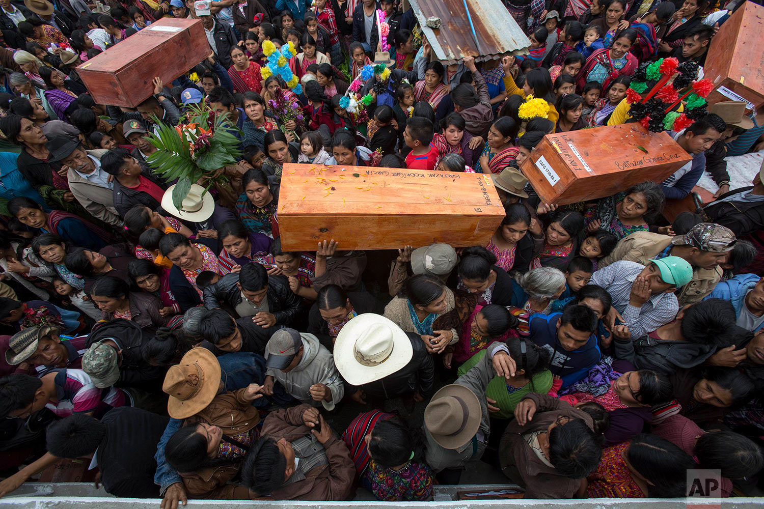 People carry coffins with the remains of civil war victims, to place in niche graves in Santa Avelina, Guatemala, Thursday, Nov. 30, 2017. After seven years of work by forensic anthropologists, including DNA tests to locate relatives, the remains of 172 indigenous Ixil Mayans killed during the civil war between 1978 and 1982 were buried in their community in the western mountains of Guatemala. (AP Photo/Luis Soto)