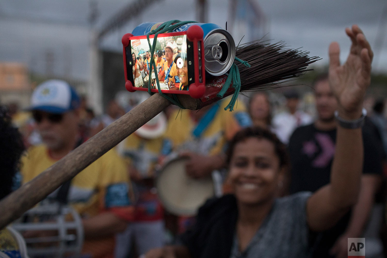 A samba band member turns a broom, beer can and rubber band into a selfie stick at the Oswaldo Cruz neighborhood, marking Samba Day in Rio de Janeiro, Brazil, Saturday, Dec. 2, 2017. The Samba Train is made up of several normal commuter metro trains filled with Samba musicians to transport revelers to the Oswaldo Cruz neighborhood for music shows, all in commemoration of National Samba Day. (AP Photo/Leo Correa)