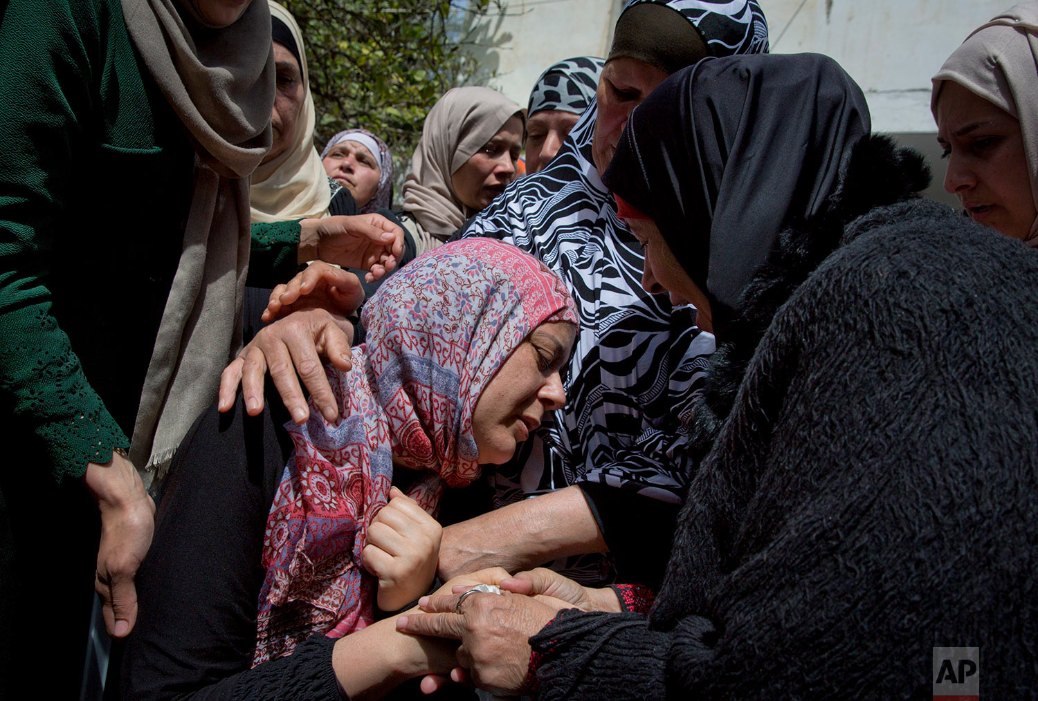 Heba Nakhleh, center is comforted by mourners during the funeral of her son Jasim Nakhleh, 17, who died of injuries sustained in clashes with Israeli forces last month, in the West Bank refugee camp of Jalazoun, at the outskirts of Ramallah, Tuesday, April 11, 2017. (AP Photo/Nasser Nasser)