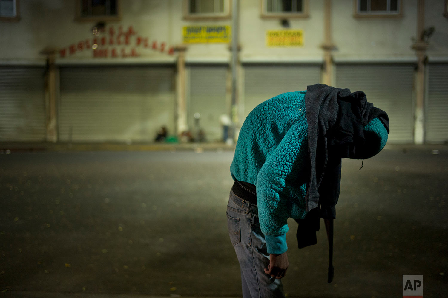 A homeless woman hunches over on a sidewalk while her partner smokes rock cocaine Thursday, Nov. 2, 2017, in the Skid Row area of downtown Los Angeles. (AP Photo/Jae C. Hong)