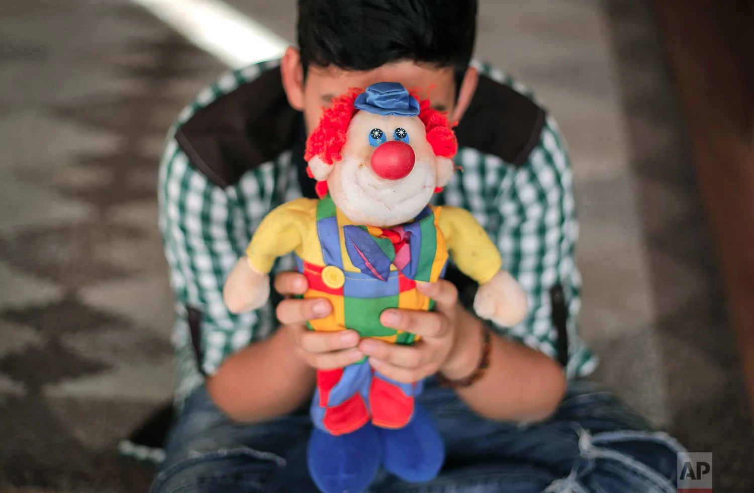 A boy living in a family-style home for abandoned children poses for a photo covering his face with a clown doll in Bucharest, Romania, on Wednesday, Nov. 1, 2017. (AP Photo/Vadim Ghirda)