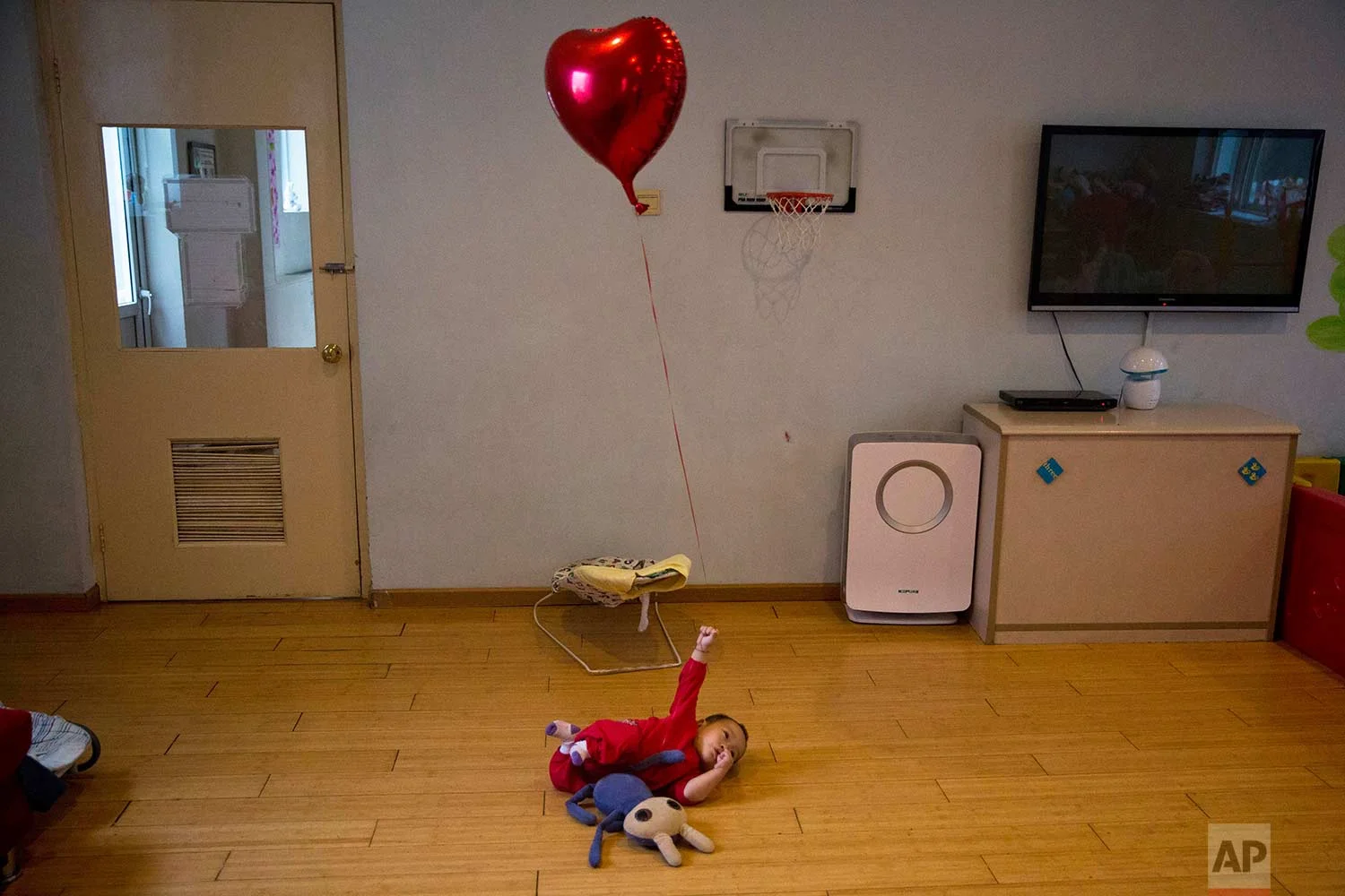 A child plays with a balloon at a foster home of the New Hope Foundation on the outskirts of Beijing, China, on Wednesday, Oct. 11, 2017. (AP Photo/Ng Han Guan)